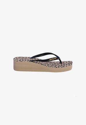 Chancla beige con cuña, con lunares negros en la plantilla y tiras negras trenzadas con detalles dorados.