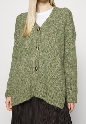 Cardigan in verde oliva lavorato a maglia, con scollo a V, tre grandi bottoni e orlo a costine. Tessuto morbido e testurizzato, vestibilità leggermente oversize e spalle cadenti.