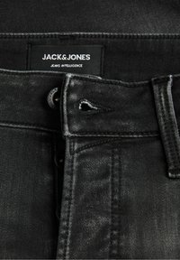 Svarta denimjeans med en klassisk femficksdesign, metallknäppning och en vävd etikett med "JACK & JONES" tydligt visad.