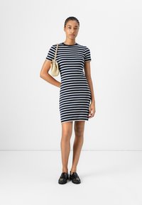 Navy and white striped short-sleeve dress, fitted silhouette, cotton blend fabric. Worn with a small beige handbag and black shoes.