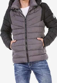 Chaqueta de plumas en gris y negro, con acolchado horizontal, cremallera frontal y dos bolsillos laterales. Diseño con capucha y acabado texturizado.
