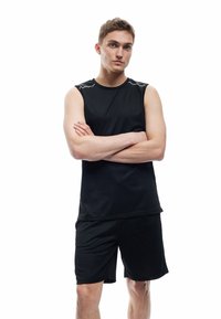 Czarny sportowy top bez rękawów, zestawiony z pasującymi szortami. Wykonany z tkaniny odprowadzającej wilgoć, o gładkiej fakturze.