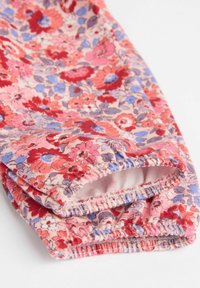 Virágmintás leggings, puha, rugalmas anyagból, rózsaszín háttérrel, piros, kék és lila virágokkal. Rugalmas bokaként záródó szegélyek.