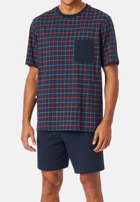 Navy plaid short-sleeve shirt with red and blue grid pattern, featuring a pocket. Paired with dark navy shorts. Cotton blend fabric.