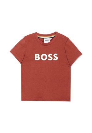 Maglietta a maniche corte per bambini color ruggine con testo bianco "BOSS" sul davanti e bottoni a pressione sul colletto della spalla sinistra.