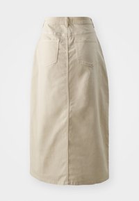 Beige puuvillane seelik sirge siluetiga, millel on kõrge vöökoht, tagakotid ja nähtavad õmblused. Sile tekstuur, põlvepikkune disain.