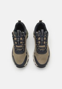 Brown and black outdoor shoes with mesh upper, rubber soles, textured patterns, and reinforced heel. Features contrasting shoelaces and logo.
