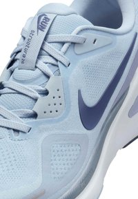 Scarpa da corsa Nike di colore azzurro chiaro con swoosh blu scuro, tomaia in rete, design con lacci e etichetta "Run Structure 26" sulla linguetta.
