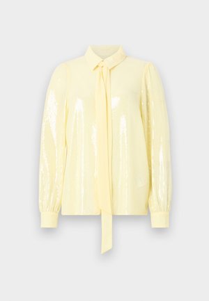 Gelbe Bluse mit langen, gepufften Ärmeln, einem gebundenen Kragen und glitzernder Textur, die das Licht reflektiert. Glattes Material, figurbetontes Design und strukturierter Kragen.
