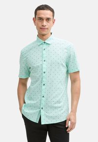 Korte mouwen, mintgroene knoopshirt met zwart stippenpatroon, kraag en rechte zoom, gemaakt van lichtgewicht stof.