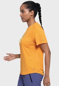 Orange short-sleeve t-shirt with a smooth texture, featuring a graphic design on the front and a logo on the sleeve.