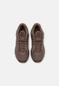 Brown athletic sneakers with mesh and synthetic materials, round toe, lace-up design, padded collar, and textured accents.