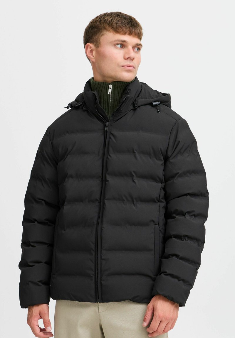 Svart vadderad jacka med dragkedja framtill, justerbar huva och elastiska ärmslut, tillverkad av slätt material med en ren, modern design.