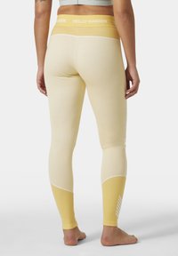 Leggings amarillos con un acabado texturizado, que presentan una cinturilla de un amarillo más claro en contraste y rayas blancas diagonales en la parte inferior de la pierna.