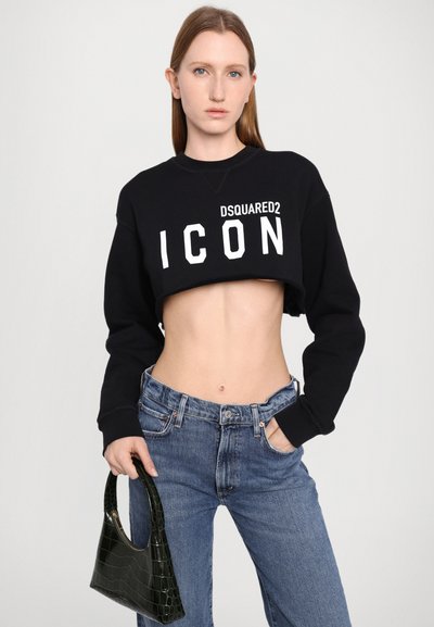 Čierna skráten�á mikina s veľkým bielym nápisom "DSQUARED2 ICON". Spárované so svetlomodrými džínsami a zelenou kabelkou z umelej kože s hadím vzorom.