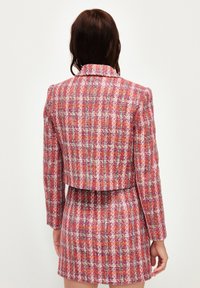 Roze en oranje tweed blazer met een cropped ontwerp, lange mouwen, een geknipt kraag en een subtiel textuurpatroon. Achteraanzicht weergegeven.