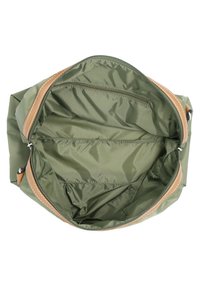 Otwarta zielona torba z nylonu z brązowymi skórzanymi wykończeniami, pokazująca wnętrze z zamykaną kieszonką na zamek i otwartymi przegródkami.