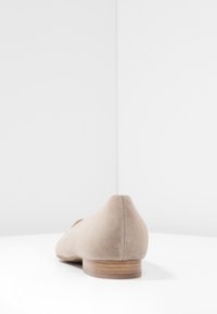 Ballerines en daim beige avec un bout arrondi et un petit talon en bois. Texture lisse, design minimal et couture subtile le long de la couture arrière.