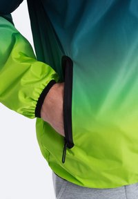 Lätt jacka med en ombre-design som sträcker sig från mörk teal till ljusgrön, med elastiska manschetter och en dragkedjeficka på sidan.