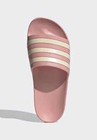 Ružová nazúvacia šľapka s textúrovaným vrchom a tromi horizontálnymi krémovými pruhmi. Podrážka je plochá a hladká, s zaobleným tvarom.