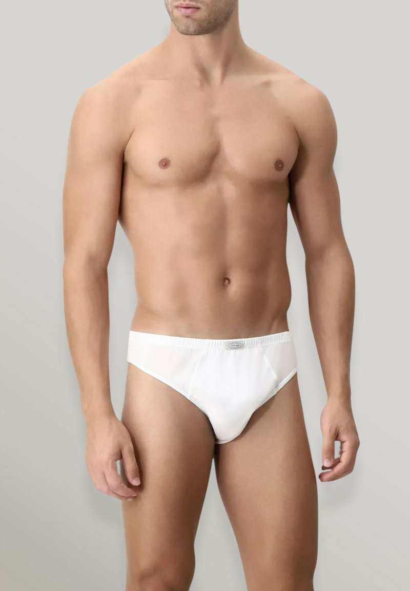 Slip in cotone bianco da uomo con design aderente, cintura elasticizzata e cuciture minime, esposti su uno sfondo neutro.