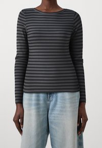Långärmad topp i ribbat tyg med ett mönster av svarta och mörkgrå ränder. Rund halsringning och figurnära siluett.