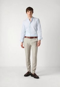 Hellblaues Hemd mit Knöpfen und langen Ärmeln, beige maßgeschneiderte Hose, brauner Ledergürtel und dunkle Schuhe, insgesamt mit glatter Textur.