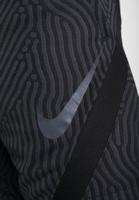 Pantalones cortos deportivos negros con franjas grises texturizadas, una cintura elástica negra suave y un logo reflectante de Nike en el lateral.
