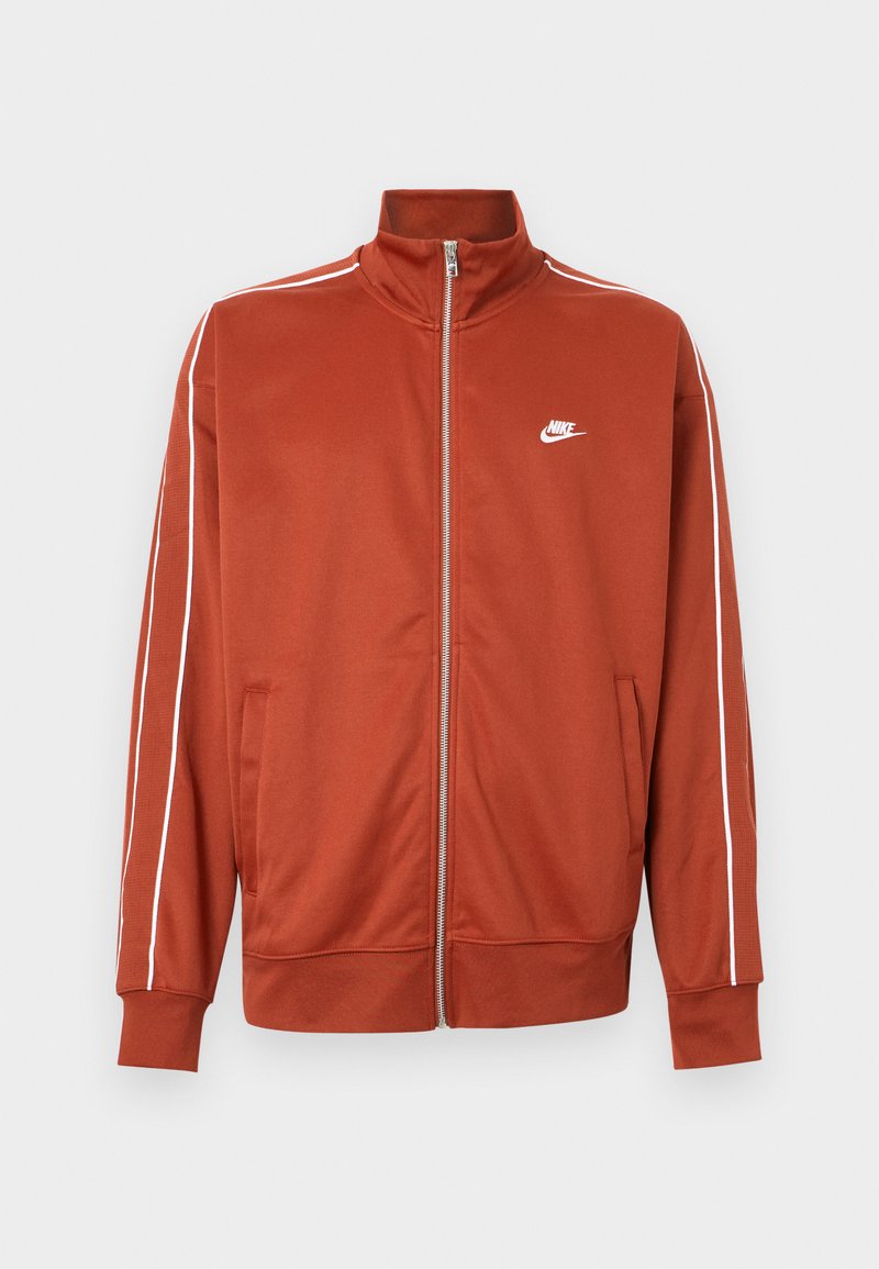 Giacca sportiva arancione ruggine con cerniera, bordatura bianca sulle maniche e piccolo logo Nike bianco sul petto sinistro.
