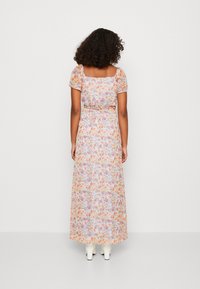 Abito lungo con maniche a palloncino corte, motivo floreale arancione e viola su sfondo chiaro, vita cinte e gonna svasata.