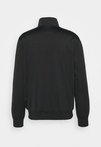 Chaqueta negra hecha de tejido suave, con cuello alto, mangas largas y puños y dobladillo elásticos. Sin patrones ni acentos visibles.