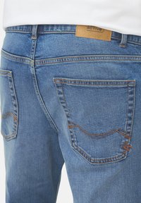 Lichtblauwe spijkerbroek van denim met een gestructureerde afwerking, voorzien van twee achterzakken, contrasterende stiksels en een leren label op de tailleband.