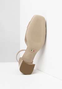 Beige high-heeled sandal with a textured sole. Adjustable strap, square heel, and branding detail on the sole. Made in Italy, size 37.