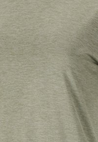 Tela de color verde claro, texturizada, con un patrón sutilmente mezclado, que presenta una apariencia suave, ligeramente jaspeada y un acabado liso.