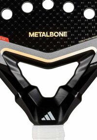 Palette noire avec une surface texturée, comportant de multiples perforations et une poignée en forme de V prononcée. Marque "METALBONE" en doré bien visible.