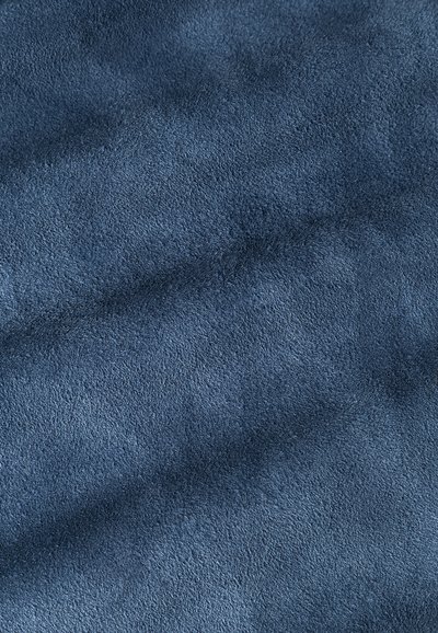 Námornícka modrá semišová látka s jemným, textúrovaným povrchom. Materiál vyzerá pružne, s jemnými variáciami svetla a tieňa.