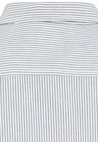 Chemise en coton avec un col boutonné, arborant des rayures verticales alternées en gris clair et foncé, avec une texture fine sur toute la surface.