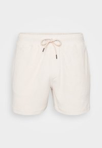 Shorts en terry de coton blanc avec une taille élastique et un cordon de serrage. Texture lisse, longueur au-dessus du genou, design simple sans poches.