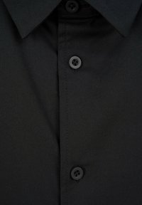 Czarna koszula zapinana na guziki z klasycznym kołnierzykiem, o gładkiej teksturze, z czterema okrągłymi czarnymi guzikami i pionowym plisem z przodu.