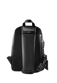 Mochila negra con un frente de cuero liso, panel trasero de malla, correa ajustable y un bolsillo con cremallera lateral. Diseño minimalista con acento de logo.