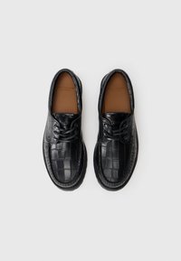 Black leather shoes featuring a crocodile texture, round toe, and lace-up design with a brown inner lining and stitched accents.