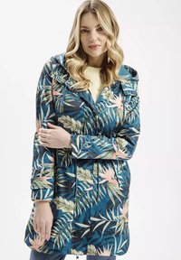 Kwiatowy płaszcz przeciwdeszczowy w odcieniach niebieskiego z zielonymi i różowymi tropikalnymi wzorami, z wysmukloną talią, zapięciem na zamek i kapturem. Gładka tekstura.