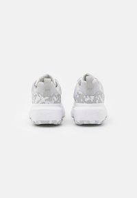 Pár bílých a šedých tenisek se vzorovanými detaily a silnými podrážkami, zobrazených zezadu na bílem pozadí.