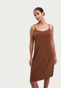 Brązowa sukienka bez rękawów z gładkiej tkaniny z ozdobnym wykończeniem dekoltu w kształcie fali. Ma luźny krój i sięga tuż nad kolano.