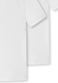 T-shirt bianchi di cotone esposte affiancate, con maniche corte, scollatura a giro e una finitura liscia e uniforme.