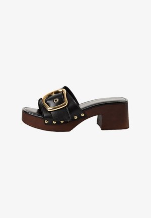 Sandale à glissière en cuir noir avec une large bride, une boucle dorée, une découpe ronde et des accents de clous bronze sur un talon à blocs de couleurs alternées.