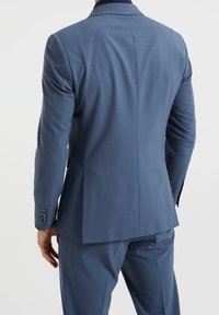 Skräddarsydd blå kavaj med slagkrage, enkel slits och treknappar vid ärmarna i ett slätt, strukturerat tyg.