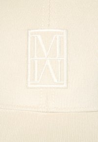 Beige Kordhut mit einem erhabenen, gestickten Logo in der Mitte. Die Textur ist gerippt, mit sichtbaren Nähten entlang des Schirms.