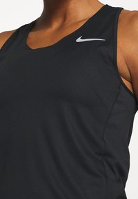 Top atletico senza maniche di colore nero, realizzato in tessuto liscio, con design a scollo a V e un piccolo logo Nike argento sulla spalla sinistra.