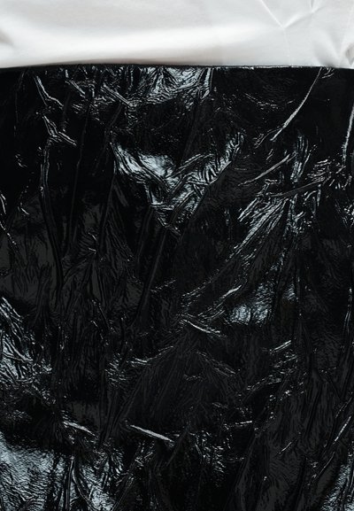 Μαύρο γυαλιστερό ζαρωμένο ύφασμα από δερματίνη που καλύπτει τον κορμό, με λευκό μαλακό ύφασμα ορατό στην επάνω άκρη.